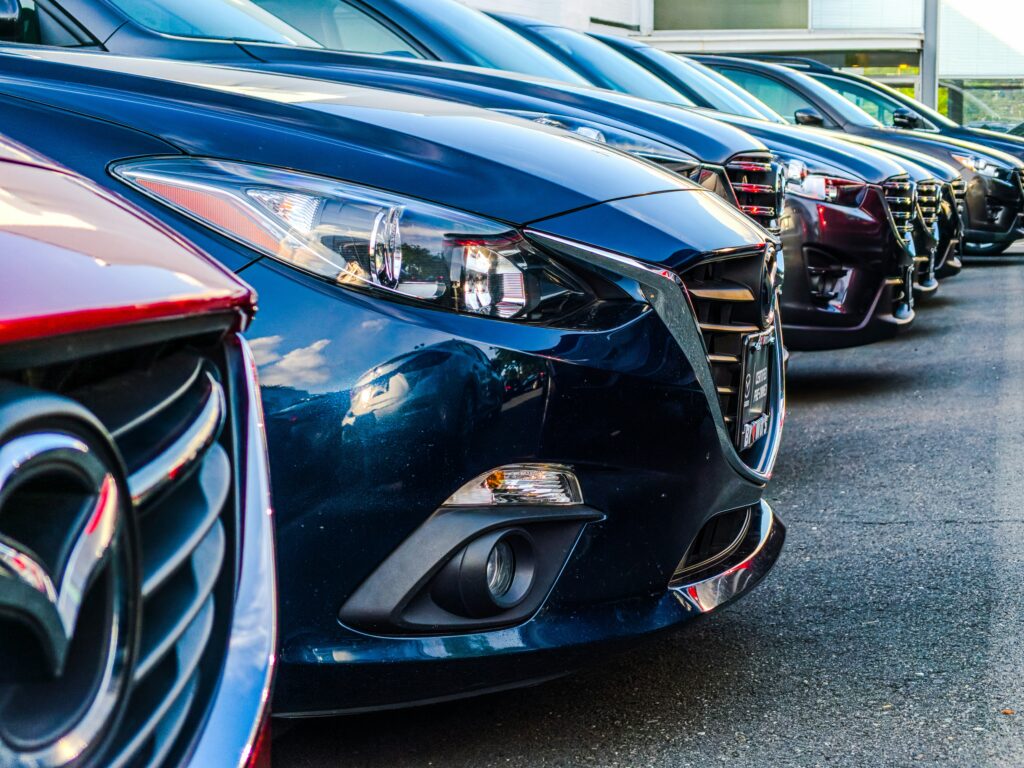 Home 3 A row of parked cars showcasing different models and colors, primarily in shades of blue, red, and black.
